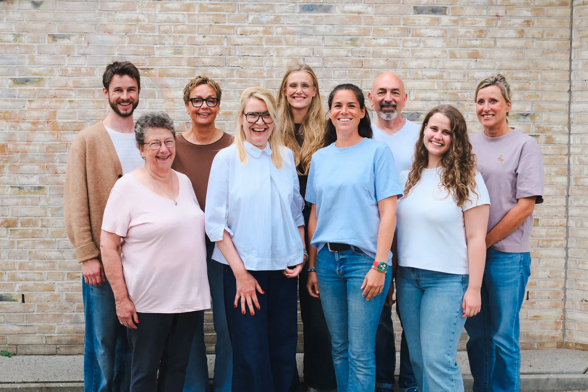 Das Team der Physiotherapie Freiraum vor einer hellen Ziegelwand