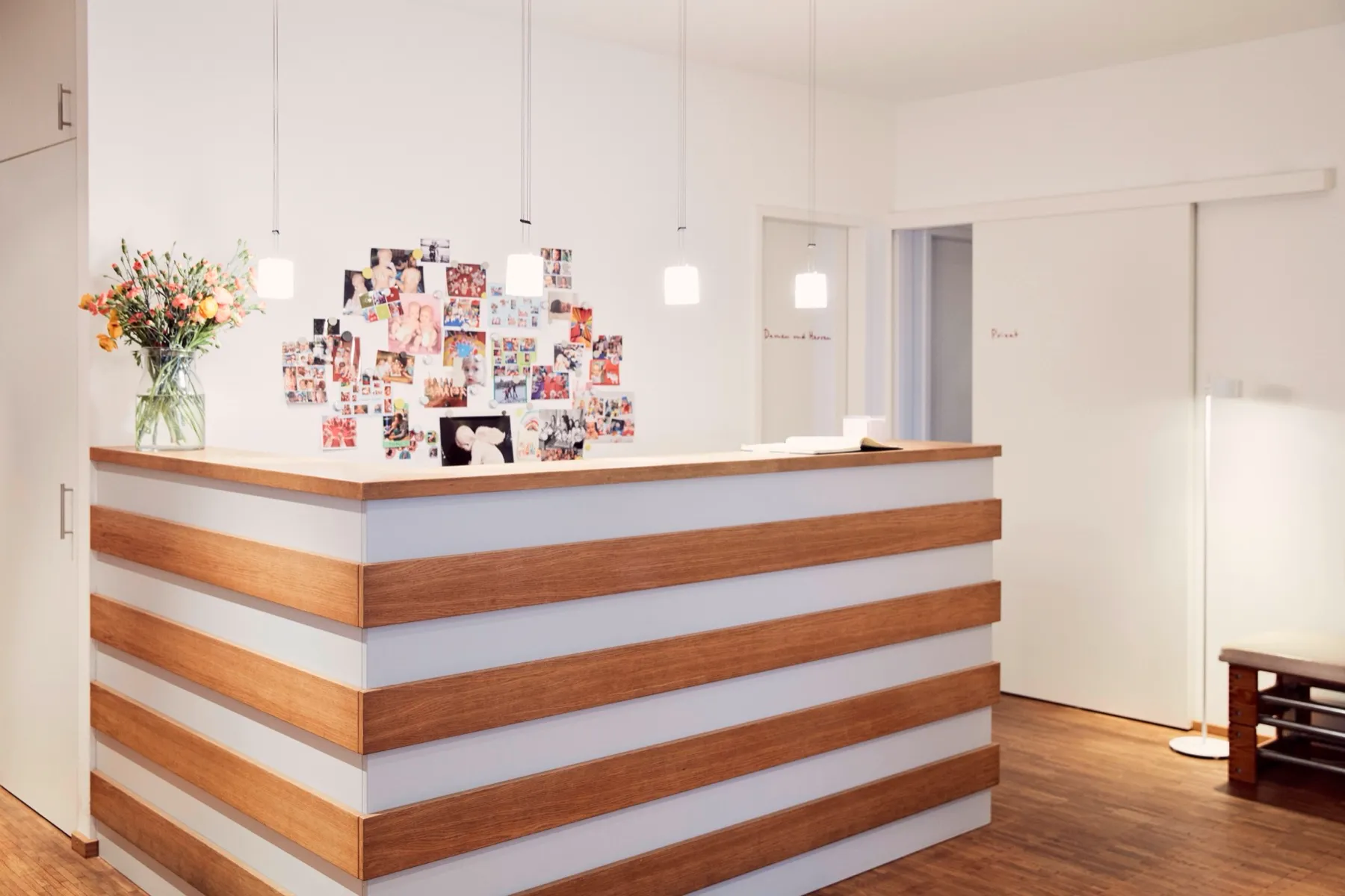 Empfangsbereich der Physiotherapie Freiraum mit hellem Holz und frischen Blumen